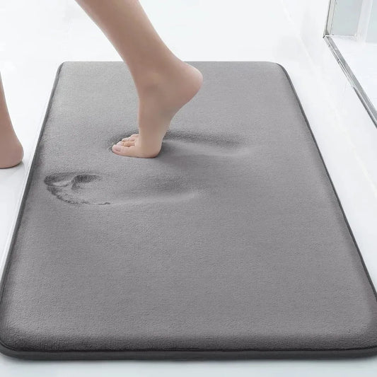 Grey cushioned memory foam bath mat with a foot pressing into its soft surface
